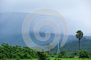 Scenic rural landscape of Kampot, South Cambodia. ItÃ¢â¬â¢s raining over the mountain and paddy field, power line pylon in